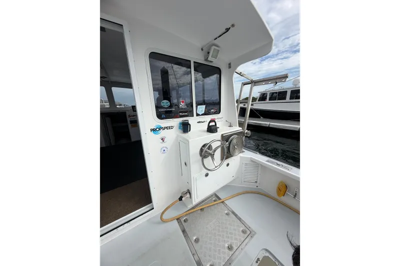 Slide: The Image of 2018 H&H Marine Osmond Beal boat deck with steering wheel and dock view. - 21