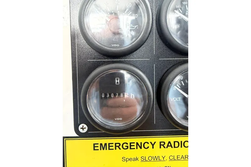 Slide: The Image of Dashboard gauges of 2018 H&H Marine Osmond Beal boat, showing engine hours and emergency radio instructions. - 67