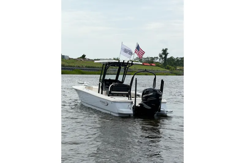 Slide: The Image of 2022 Robalo 266 Cayman boat on water with flags and Mercury engine. - 7