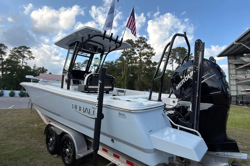 Slide: The Image of 2022 Robalo 266 Cayman boat with Mercury engine, parked outdoors under a blue sky. - 45