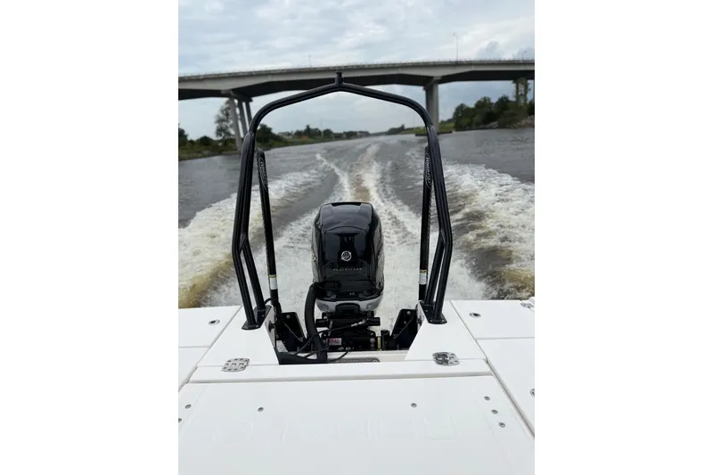 Slide: The Image of 2022 Robalo 266 Cayman boat cruising under a bridge on a river. - 27