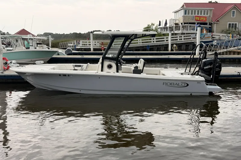 Slide: The Image of A 2022 Robalo 266 Cayman docked. It features a sleek design and an outboard motor. - 8