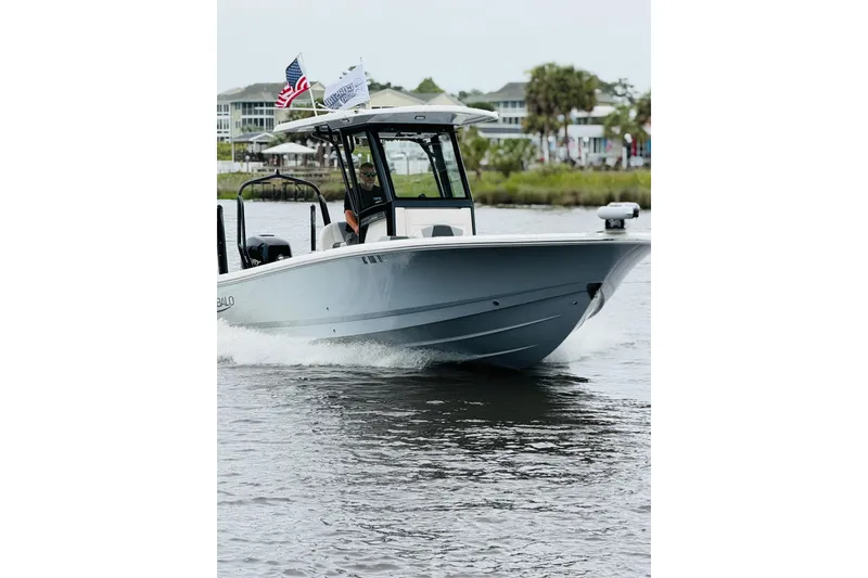 Slide: The Image of A 2022 Robalo 266 Cayman boat cruising on a waterway. It features a white hull and flags. - 4