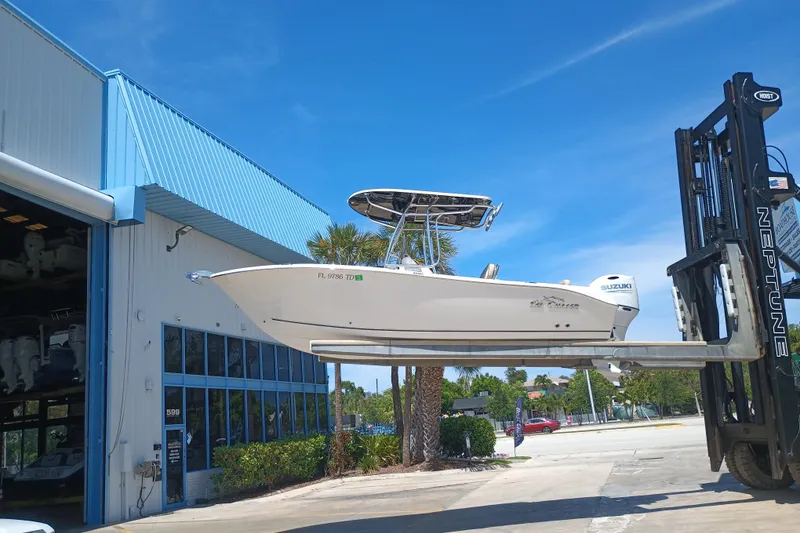 Slide: The Image of 2022 Sea Chaser 22 HFC boat lifted by forklift near a blue-roofed building. - 11