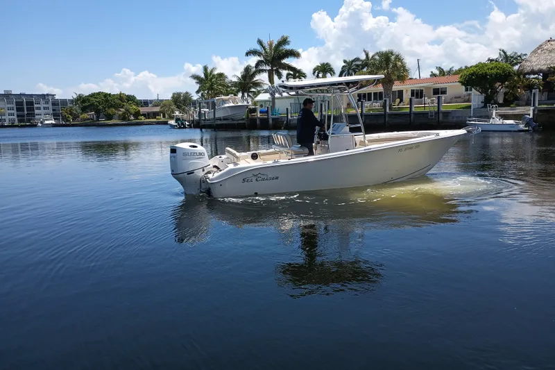 Slide: The Image of 2022 Sea Chaser 22 HFC boat cruising on a calm waterway with palm trees in the background. - 3
