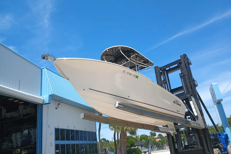 Slide: The Image of 2022 Sea Chaser 22 HFC boat lifted by forklift near blue-roofed building. - 10