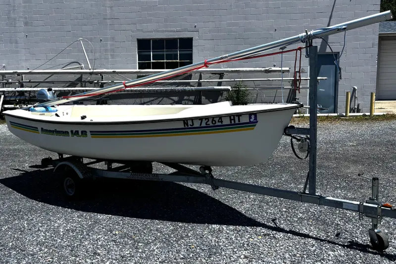 Slide: The Image of 2018 American Sail 14.6 sailboat on trailer, parked outdoors near a building. - 2