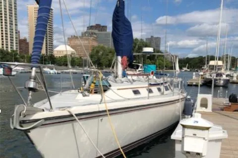 The Image of 1990 Catalina 42 sailboat docked in a marina with cityscape background. - 1