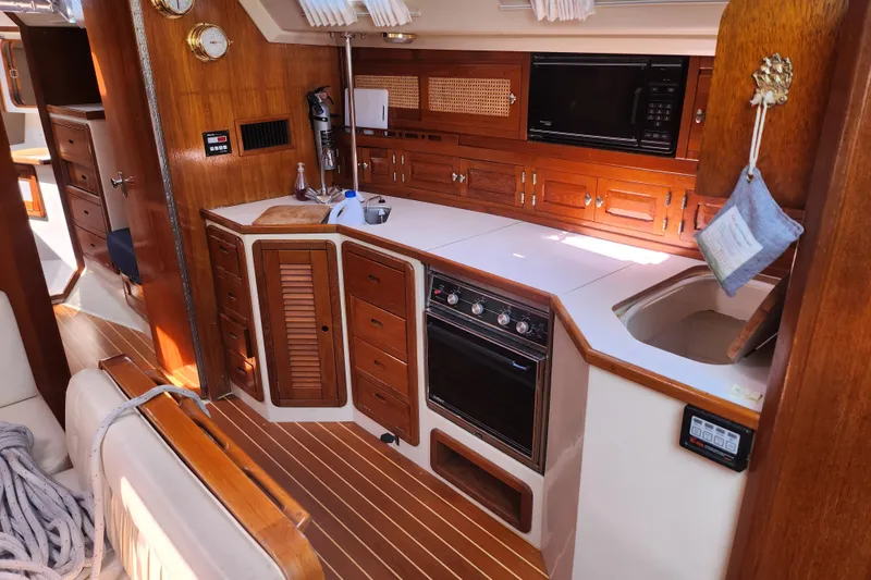 Slide: The Image of Interior of a 1990 Catalina 42 sailboat featuring a wooden galley kitchen. - 18