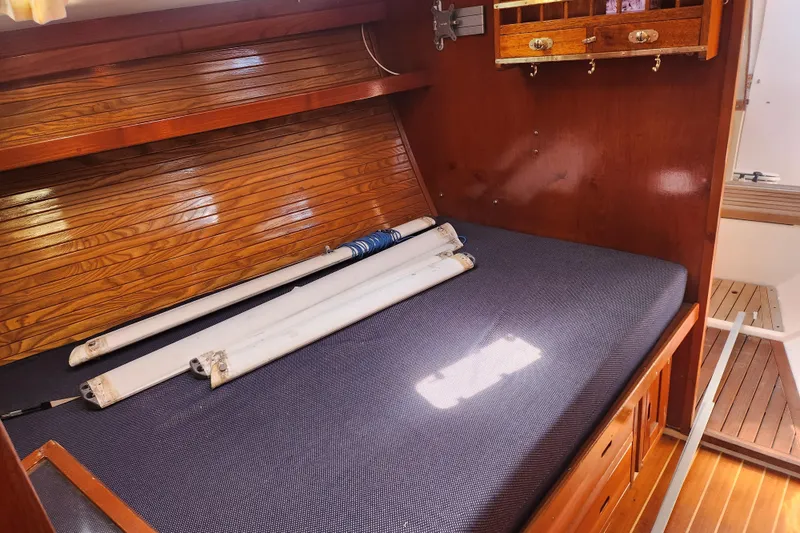 Slide: The Image of Interior of 1990 Catalina 42 sailboat with wooden cabinetry and folded sails on bed. - 20