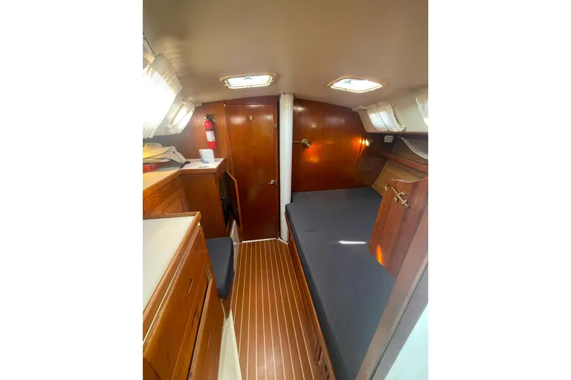 Slide: The Image of 1990 Catalina 42 yacht interior with wooden cabinetry and cozy sleeping area. - 6