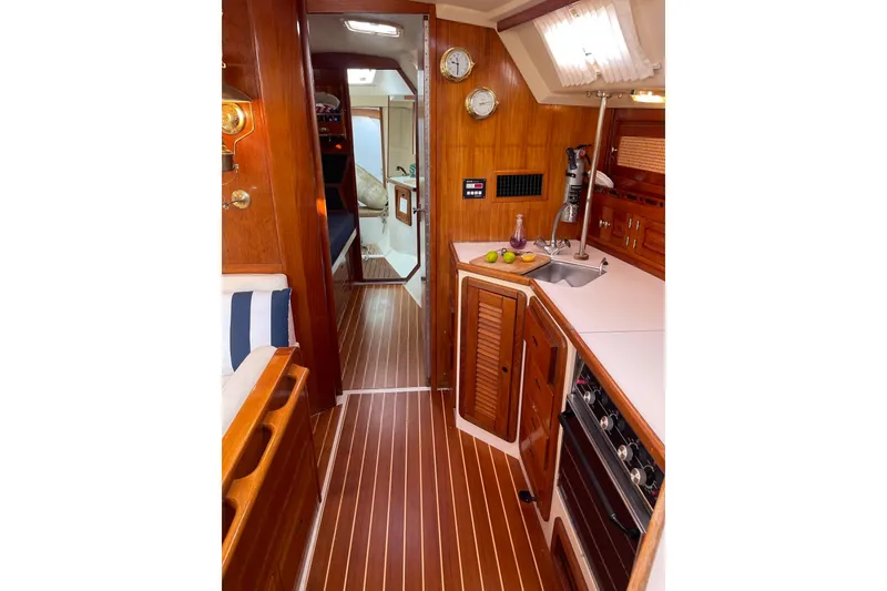 Slide: The Image of Interior of a 1990 Catalina 42 sailboat featuring a wooden galley and cozy cabin. - 9