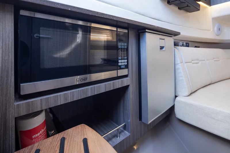 Slide: The Image of Interior of 2025 Sea Ray SLX 400 featuring microwave, mini-fridge, and seating area. - 17