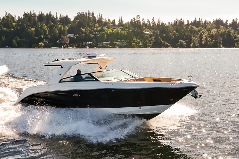 Slide: The Image of 2025 Sea Ray SLX 400 cruising on a scenic lake with forested shoreline. - 2
