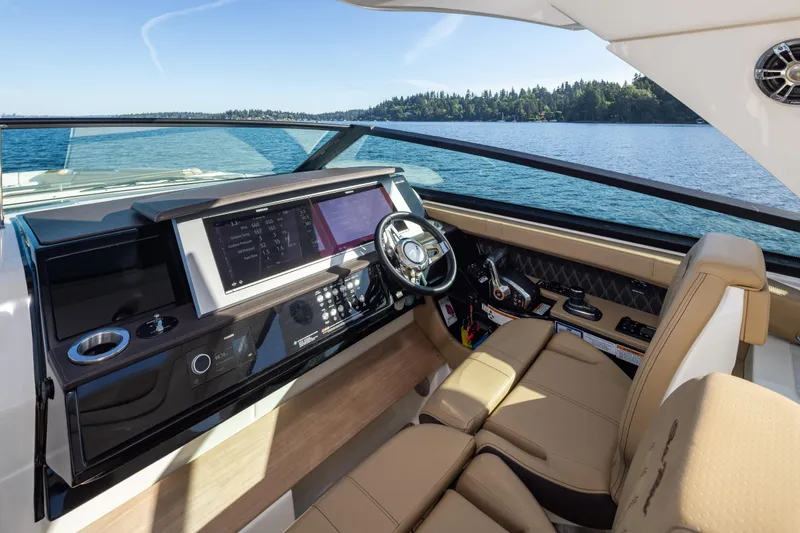 Slide: The Image of 2025 Sea Ray SLX 400 helm with modern controls, overlooking serene water and forested shoreline. - 23