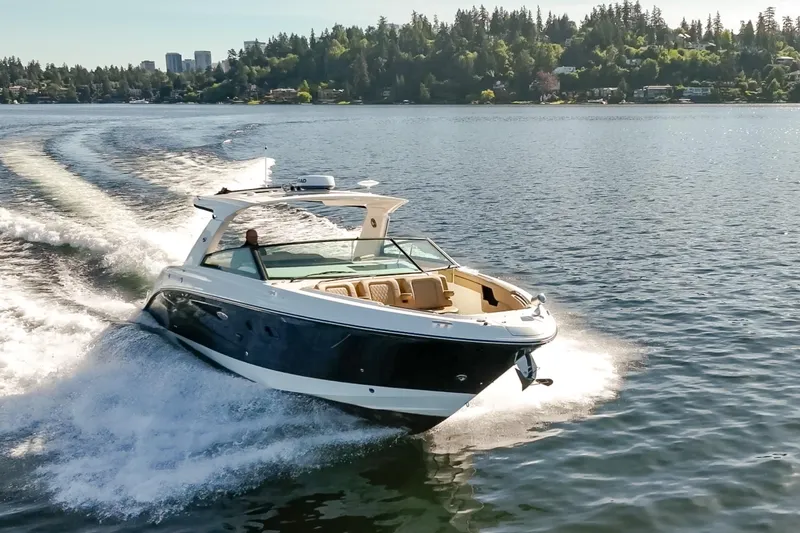 Slide: The Image of 2025 Sea Ray SLX 400 cruising on a scenic lake with forested shoreline. - 3