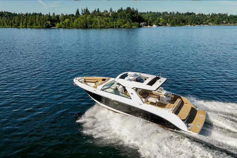 Slide: The Image of 2025 Sea Ray SLX 400 cruising on a serene lake with lush green shoreline. - 4