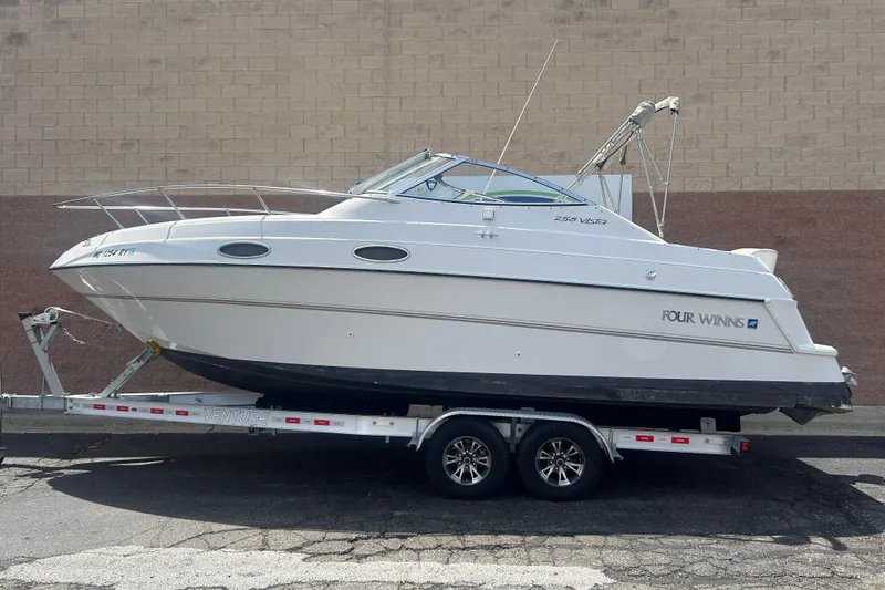 The Image of 1998 Four Winns 258 Vista boat on trailer, parked against a brick wall. - 0