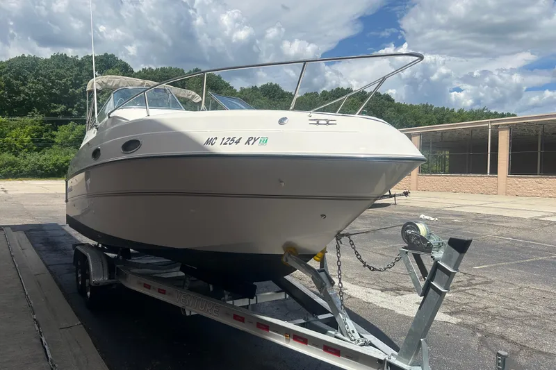 Slide: The Image of 1998 Four Winns 258 Vista boat on trailer, parked outdoors under cloudy sky. - 1