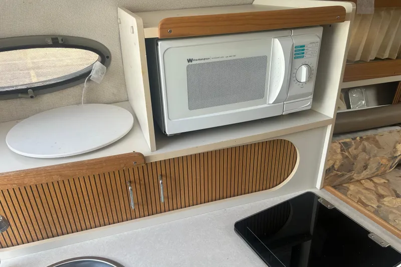 Slide: The Image of 1998 Four Winns 258 Vista interior with microwave, wooden cabinets, and countertop. - 15