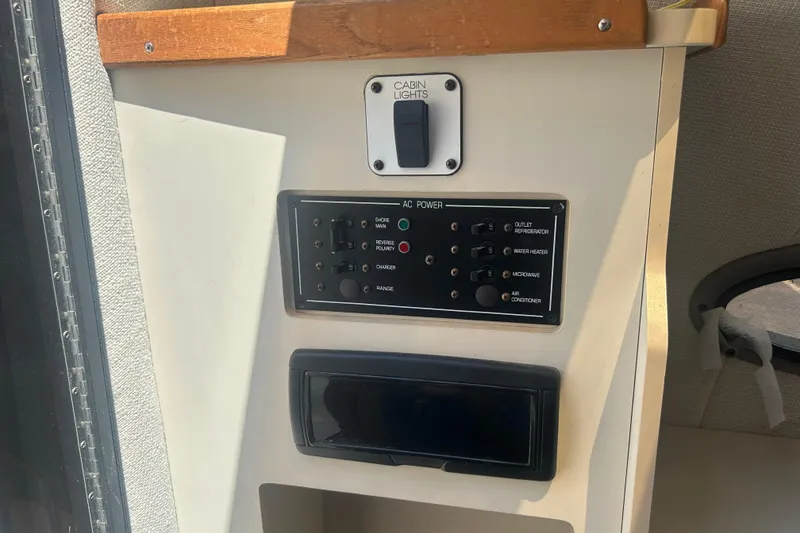 Slide: The Image of 1998 Four Winns 258 Vista cabin control panel with AC power switches and cabin lights. - 16
