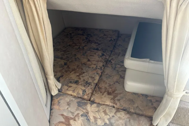 Slide: The Image of 1998 Four Winns 258 Vista cabin interior with patterned cushions and beige curtains. - 17