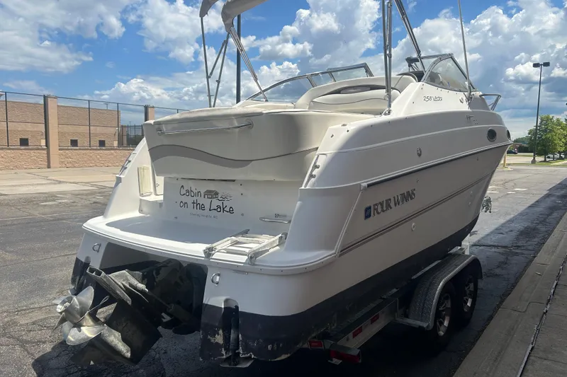 Slide: The Image of 1998 Four Winns 258 Vista boat on trailer, parked outdoors under a cloudy sky. - 4