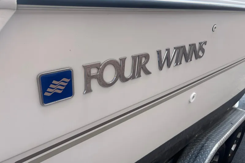 Slide: The Image of 1998 Four Winns 258 Vista boat logo on white hull with blue emblem. - 5