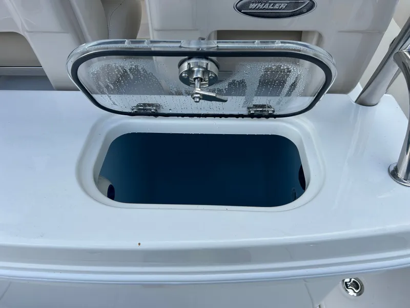 Slide: The Image of An open storage compartment on a Boston Whaler 250 Outrage boat, featuring a transparent lid. - 13