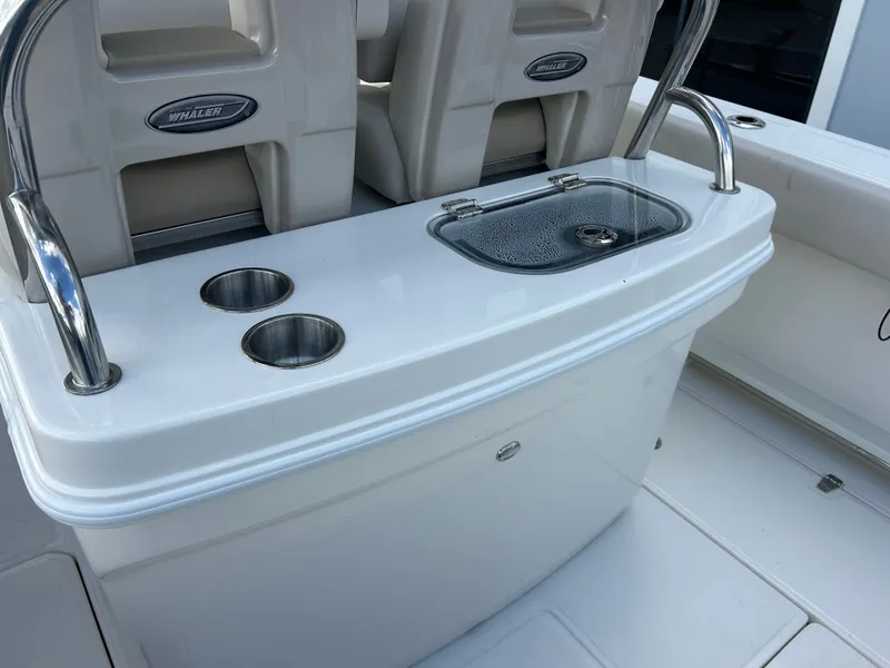 Slide: The Image of The image shows the cockpit of a 2027 Boston Whaler 250 Outrage with stainless steel holders and a sink. - 12
