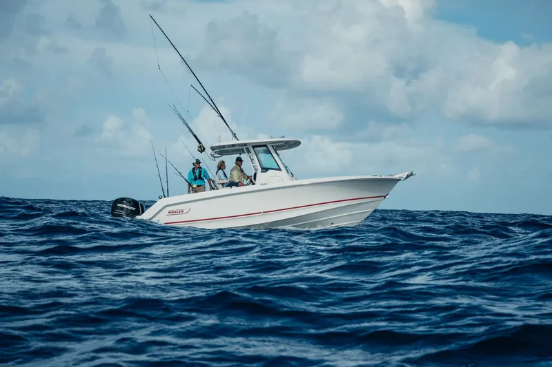 Slide: The Image of A 2027 Boston Whaler 250 Outrage navigates choppy waters with several people on board. - 3