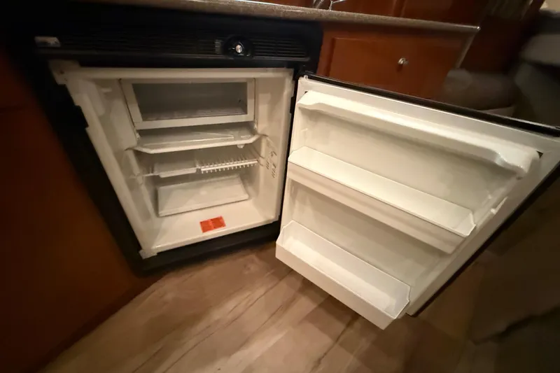 Slide: The Image of Open refrigerator inside a 2005 Maxum 3300 SCR boat, showing shelves and storage compartments. - 39