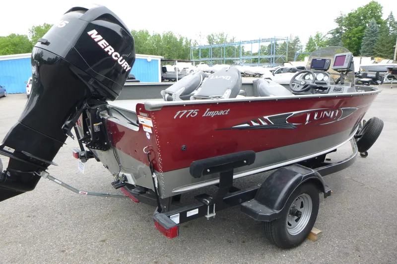 Slide: The Image of 2012 Lund 1775 Impact boat with Mercury engine on trailer, parked outdoors. - 4