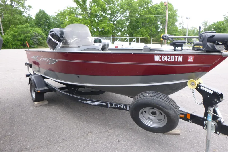 Slide: The Image of 2012 Lund 1775 Impact boat on trailer, parked outdoors with green trees in background. - 5