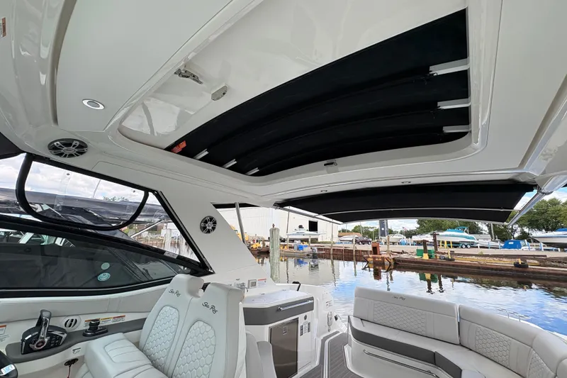 Slide: The Image of 2026 Sea Ray Sundancer 320 interior with open sunroof, dockside view. - 9