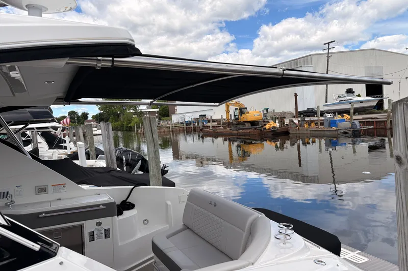 Slide: The Image of 2026 Sea Ray Sundancer 320 docked by a calm marina with industrial backdrop. - 6