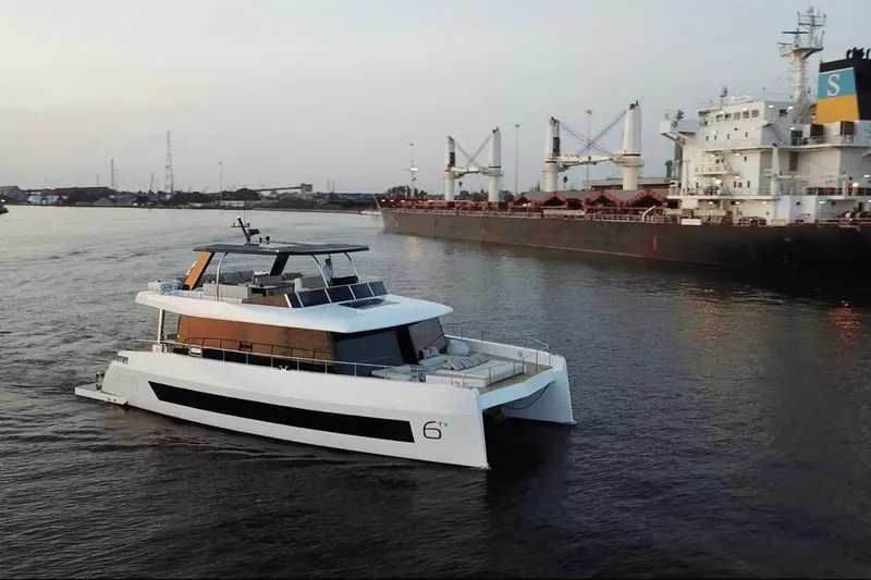 Slide: The Image of Modern 2025 Moon 60 yacht cruising near a large cargo ship in a calm harbor. - 3