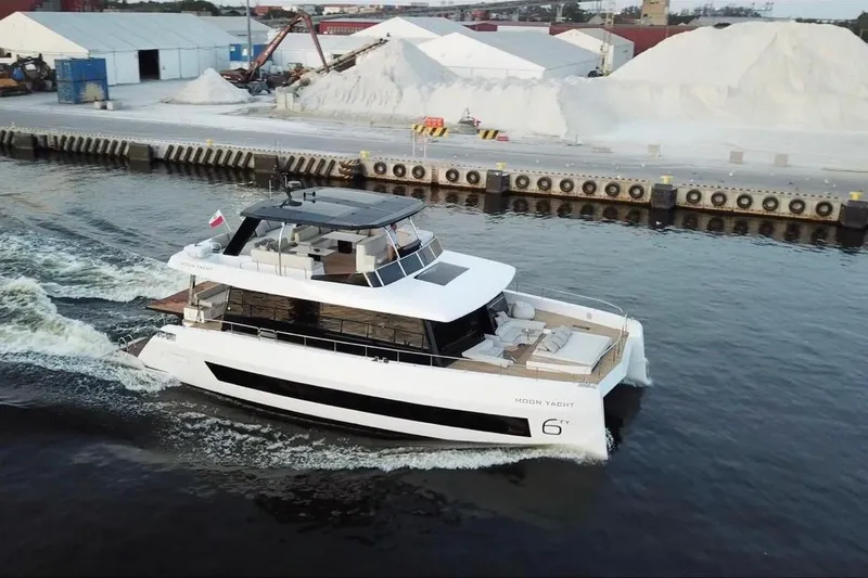 Slide: The Image of Luxurious 2025 Moon 60 yacht cruising near industrial dock, showcasing sleek design and modern amenities. - 6