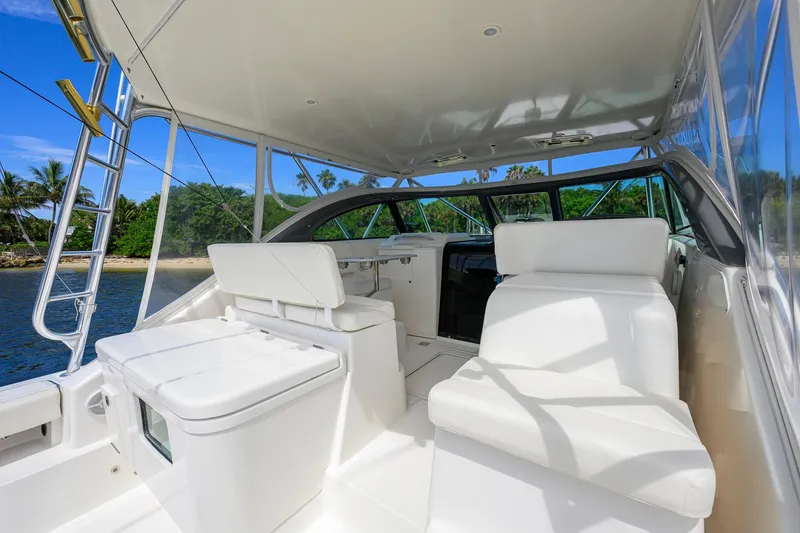 Slide: The Image of 2004 Pursuit 3800 Express yacht interior with white seating, near tropical shoreline. - 23