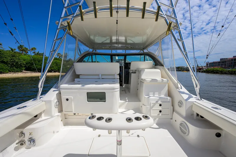 Slide: The Image of 2004 Pursuit 3800 Express yacht interior with fishing setup, docked near lush shoreline. - 3