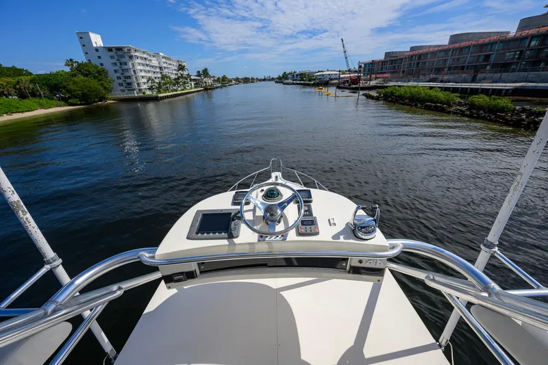 Slide: The Image of Helm view from 2004 Pursuit 3800 Express boat navigating a scenic waterway. - 58