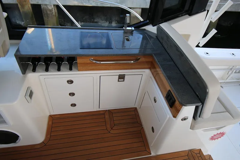 Slide: The Image of Manufacturer Provided Image: 2024 Boston Whaler 405 Conquest boat galley with wooden cabinetry and granite countertop. - 12