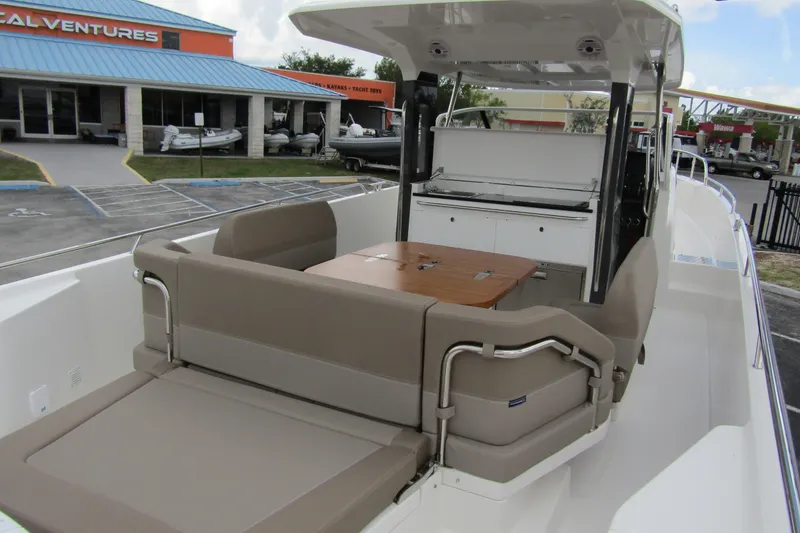 Slide: The Image of 2025 Nimbus Tender 11 boat interior with seating and table, docked near a marine store. - 46
