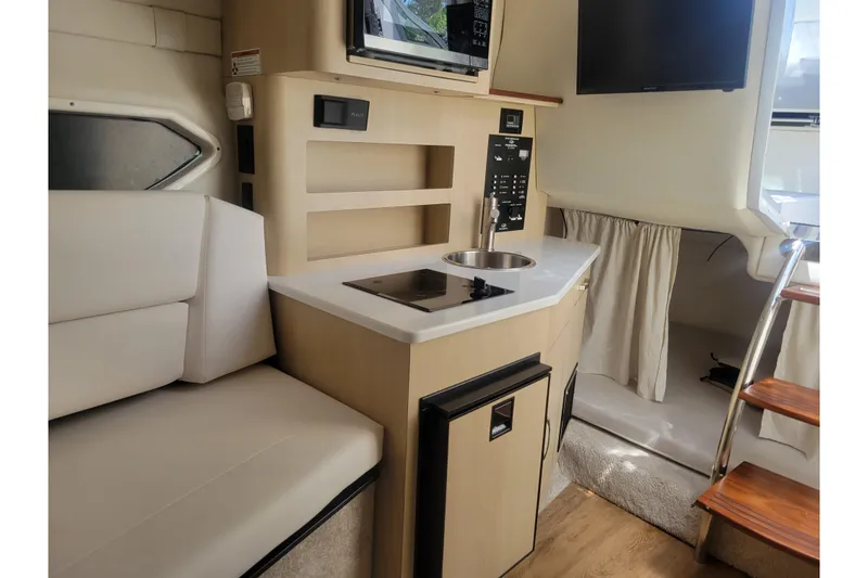 Slide: The Image of 2023 Regal 26 XO boat interior with kitchenette, seating, and stairs. - 15