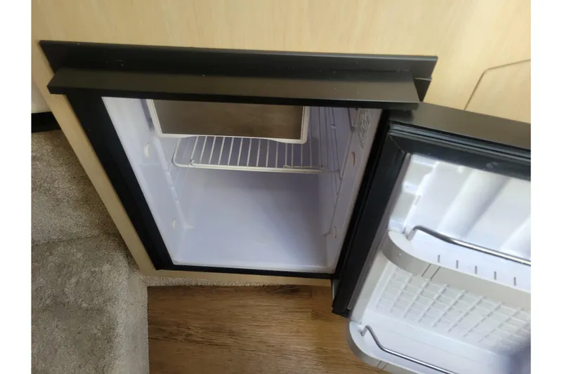 Slide: The Image of Open mini fridge inside 2023 Regal 26 XO boat, showing empty shelves. - 18