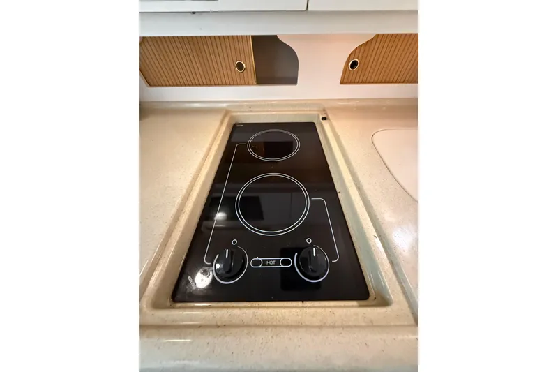 Slide: The Image of 1999 Sea Ray Sundancer 310 stovetop with two burners in a compact kitchen setting. - 18