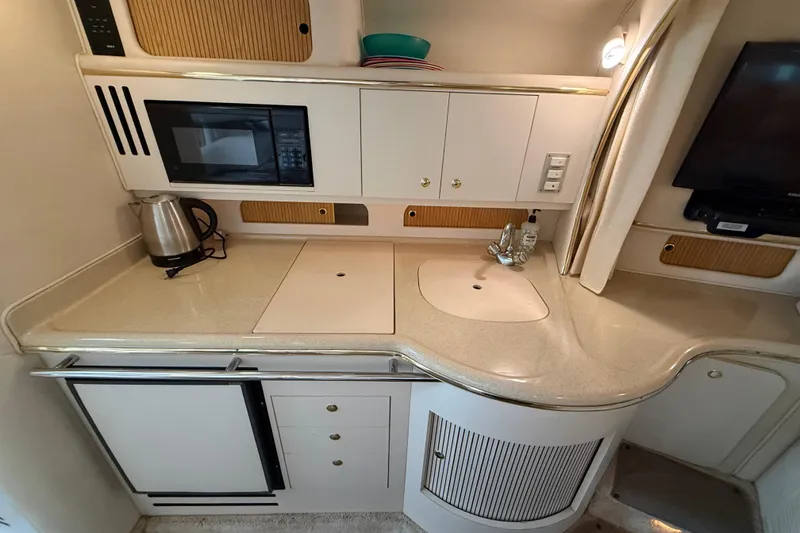Slide: The Image of 1999 Sea Ray Sundancer 310 yacht kitchen with microwave, sink, and kettle. - 20