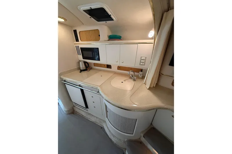 Slide: The Image of 1999 Sea Ray Sundancer 310 yacht kitchen with sink, microwave, and storage cabinets. - 21