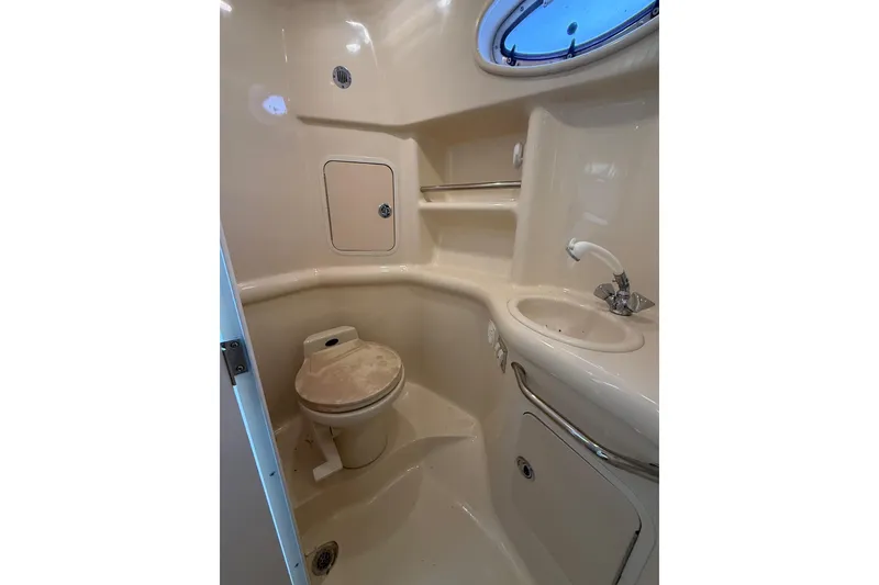 Slide: The Image of 1999 Sea Ray Sundancer 310 bathroom with toilet, sink, and storage compartments. - 23