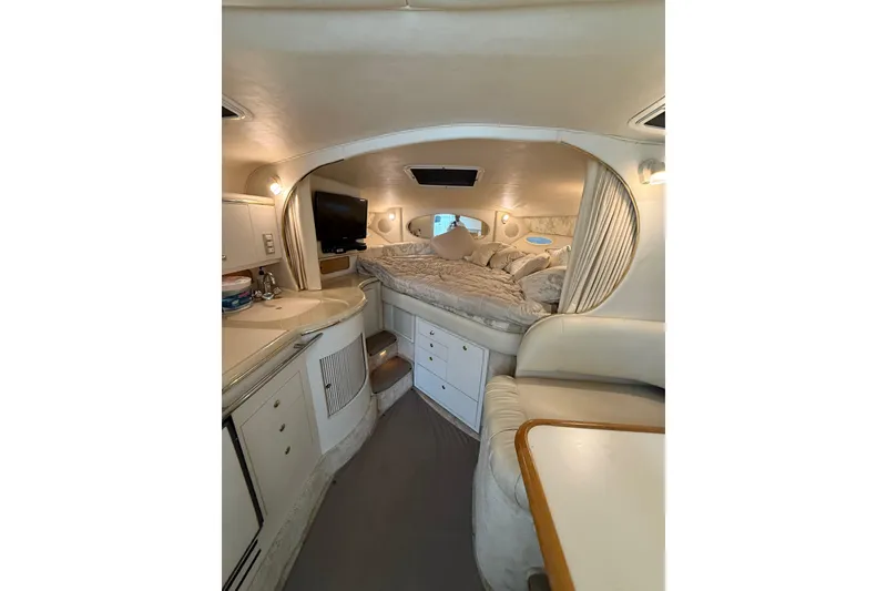 Slide: The Image of 1999 Sea Ray Sundancer 310 cabin interior with bed, TV, and kitchenette. - 26